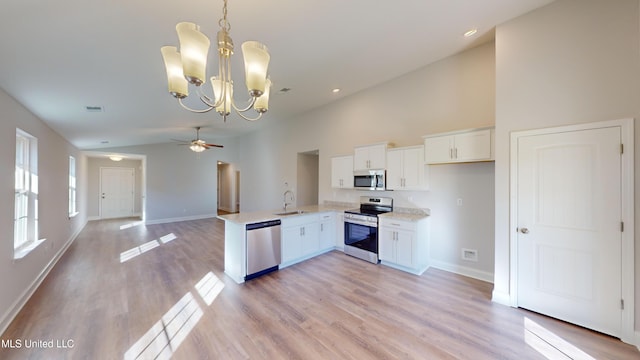 kitchen with kitchen peninsula, appliances with stainless steel finishes, sink, decorative light fixtures, and white cabinets