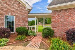 123 Munich Dr, Madison, MS 39110 - doorway to property featuring brick siding and covered porch