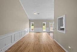 123 Munich Dr, Madison, MS 39110 - hall featuring ornamental molding, wood finished floors, a wainscoted wall, lofted ceiling, and a decorative wall