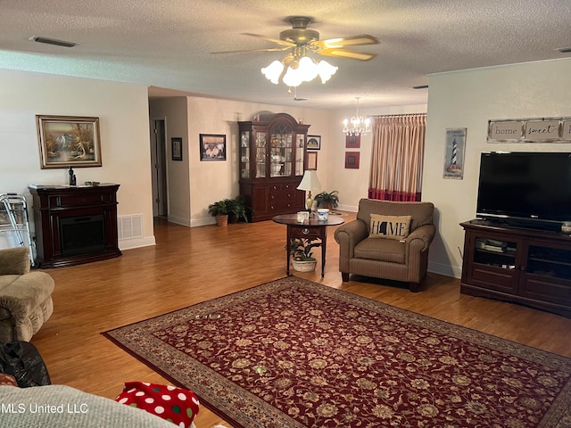 living room with a textured ceiling, hardwood / wood-style flooring, and ceiling fan with notable chandelier