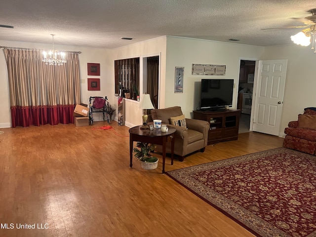 living room with hardwood / wood-style floors, a textured ceiling, and ceiling fan with notable chandelier