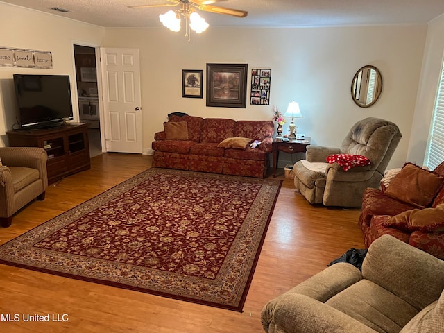 living room featuring hardwood / wood-style floors, a textured ceiling, and ceiling fan