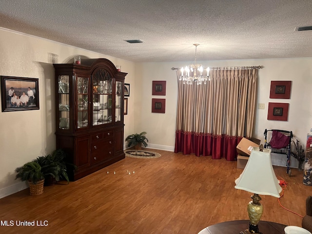 interior space featuring a textured ceiling, hardwood / wood-style flooring, and a chandelier