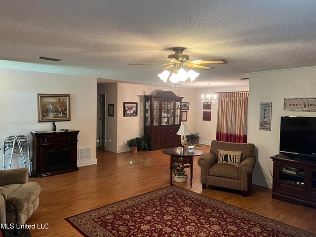 living room with wood-type flooring, a textured ceiling, and ceiling fan with notable chandelier