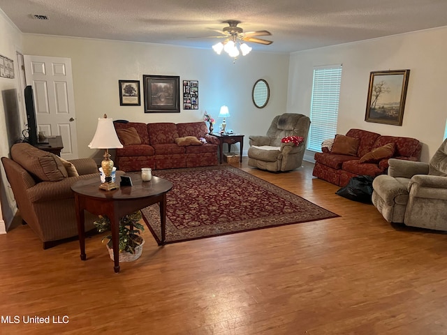 living room featuring ceiling fan, a textured ceiling, and light wood-type flooring