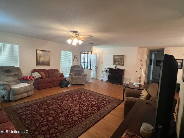 living room featuring a textured ceiling, hardwood / wood-style flooring, and ceiling fan