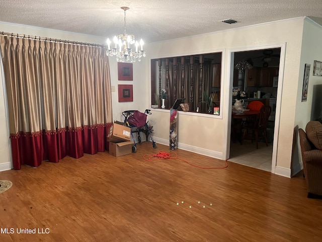 interior space featuring a textured ceiling, a notable chandelier, and hardwood / wood-style flooring