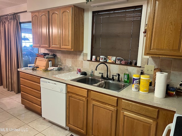 kitchen with sink, white dishwasher, backsplash, and light tile patterned floors