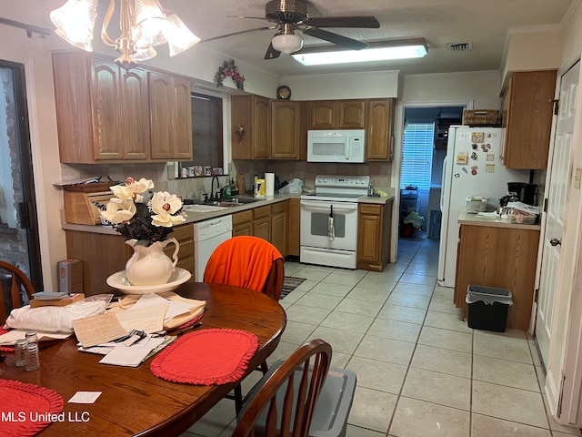 kitchen with white appliances, light tile patterned flooring, sink, ceiling fan with notable chandelier, and decorative backsplash