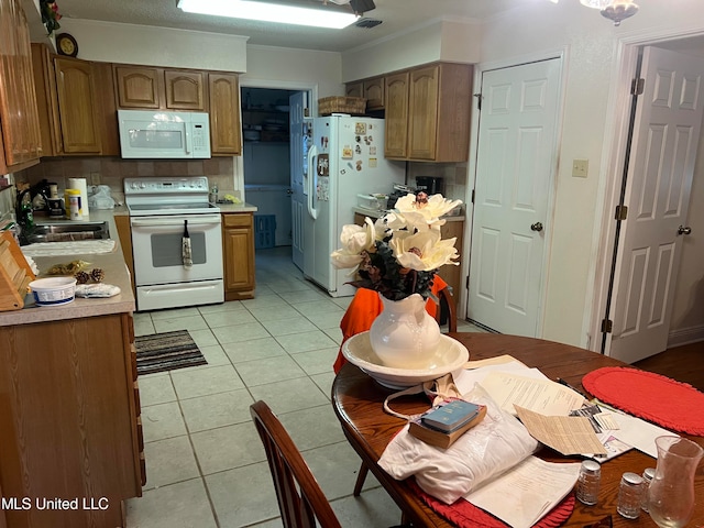 kitchen with white appliances, tasteful backsplash, sink, ornamental molding, and light tile patterned floors