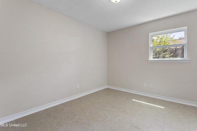 empty room with light tile patterned flooring and baseboards