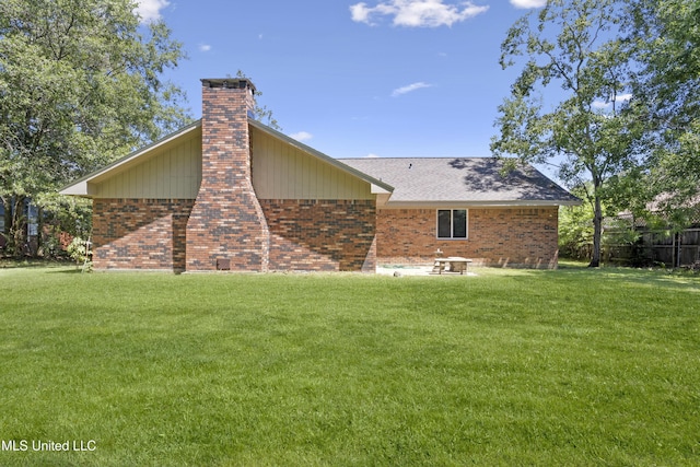 rear view of property with a lawn, brick siding, a chimney, and roof with shingles