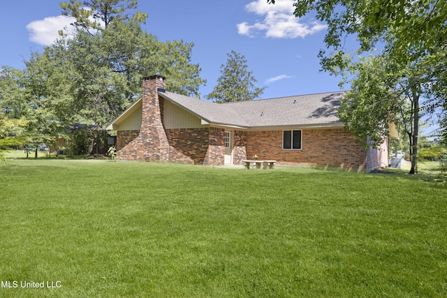 rear view of house with a lawn, brick siding, and a chimney