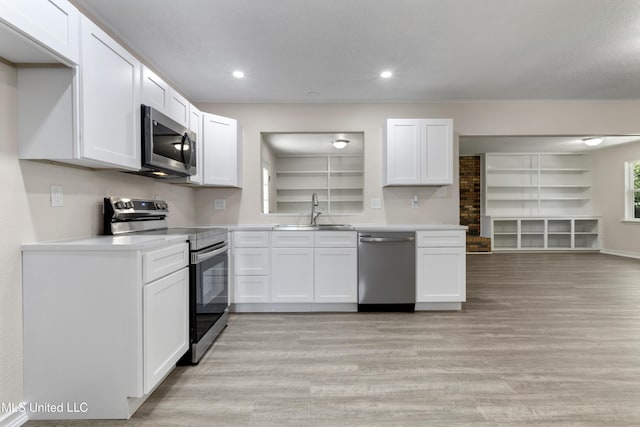kitchen with light wood-style floors, a sink, white cabinetry, and appliances with stainless steel finishes