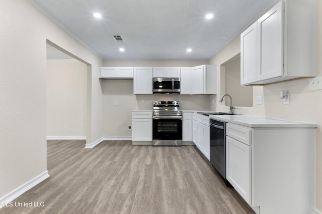 kitchen with stainless steel appliances, baseboards, a sink, and light wood-style flooring