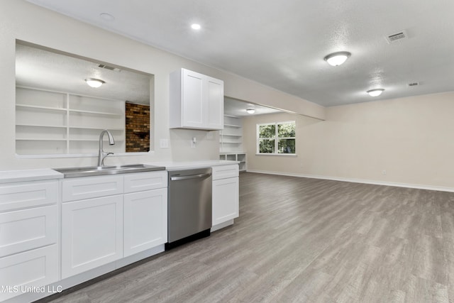 kitchen with stainless steel dishwasher, visible vents, light wood-type flooring, a textured ceiling, and a sink