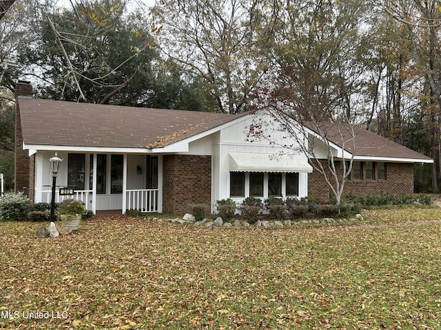 ranch-style home featuring covered porch and a front lawn