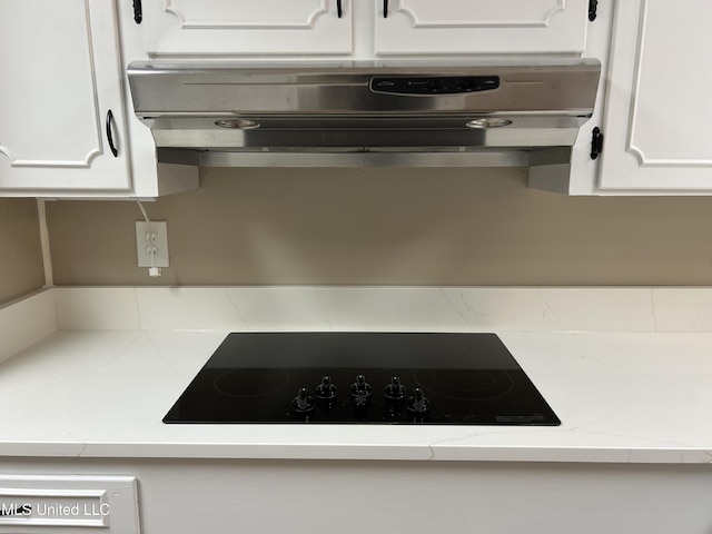 kitchen with ventilation hood, light stone counters, white cabinetry, and black electric cooktop