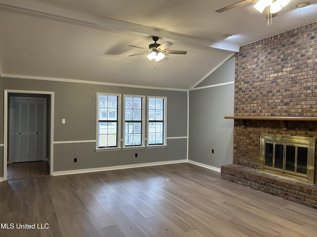 unfurnished living room featuring hardwood / wood-style flooring, lofted ceiling with beams, ornamental molding, and a fireplace