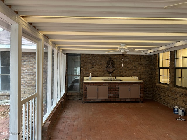 unfurnished sunroom featuring ceiling fan and sink