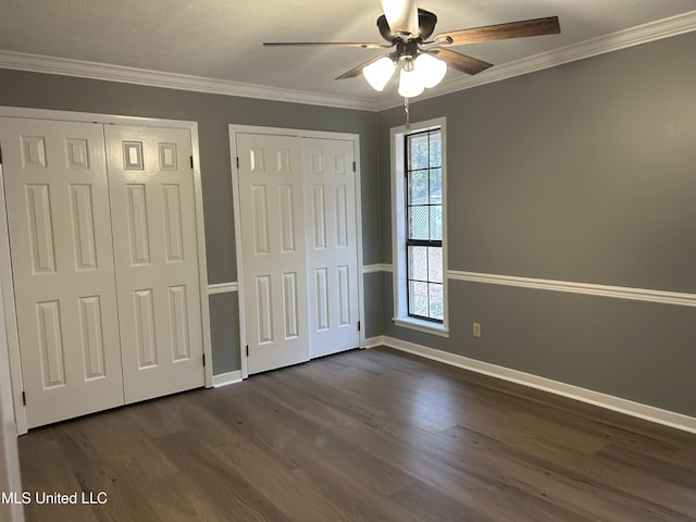 unfurnished bedroom with multiple windows, ornamental molding, ceiling fan, and multiple closets