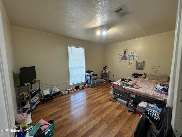 bedroom with a textured ceiling and hardwood / wood-style flooring