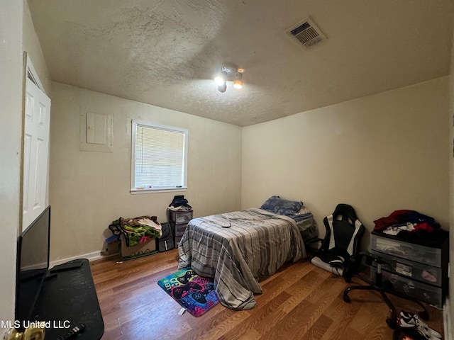 bedroom featuring hardwood / wood-style flooring and a textured ceiling