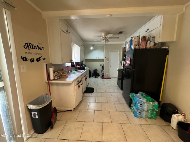 kitchen with ceiling fan, black fridge, white cabinetry, and light tile patterned floors