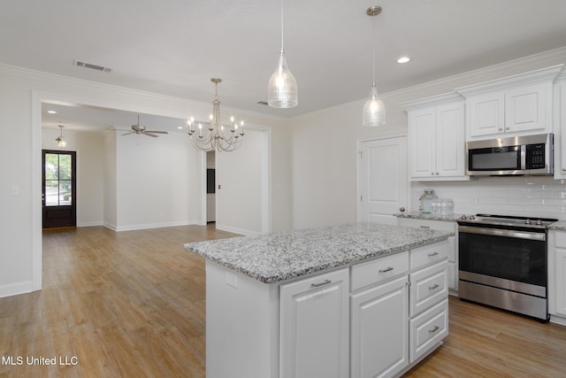 kitchen featuring white cabinetry, hanging light fixtures, stainless steel appliances, and a kitchen island