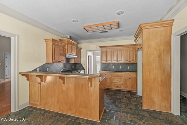 kitchen with ornamental molding, a breakfast bar, stone tile flooring, a peninsula, and backsplash