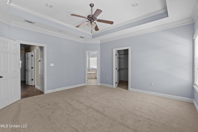 unfurnished bedroom with a raised ceiling, carpet, ornamental molding, a spacious closet, and baseboards