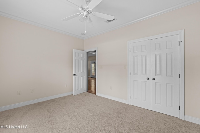 unfurnished bedroom featuring carpet flooring, ornamental molding, a closet, baseboards, and ceiling fan