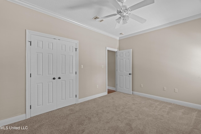 unfurnished bedroom featuring carpet flooring, ornamental molding, a closet, baseboards, and a ceiling fan