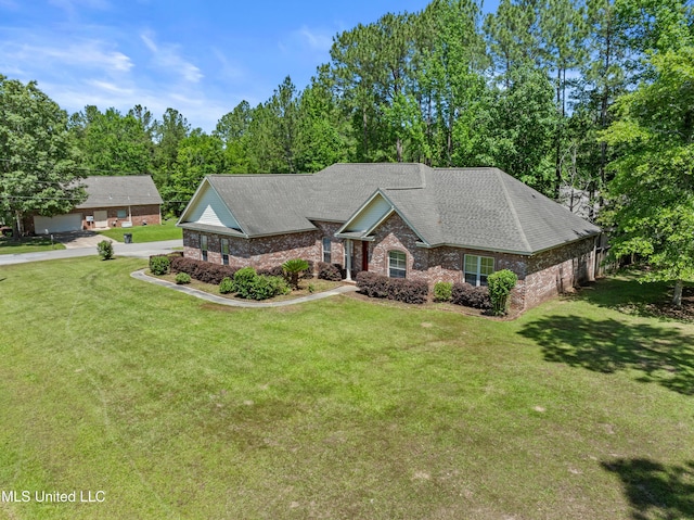 view of front of home featuring brick siding, a front lawn, a shingled roof, and view of wooded area