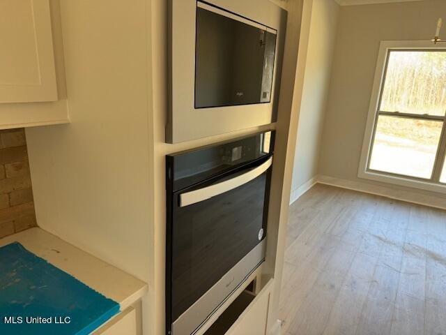 kitchen with white cabinets, light hardwood / wood-style floors, and stainless steel oven