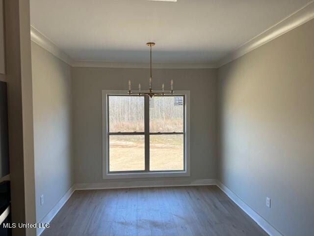 unfurnished dining area featuring hardwood / wood-style floors, a notable chandelier, and ornamental molding