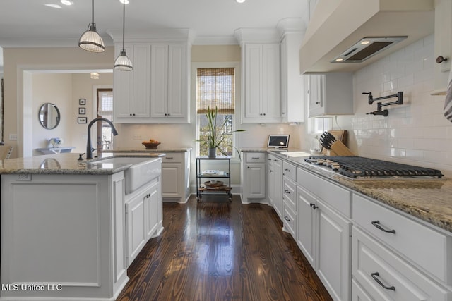 kitchen featuring a sink, wall chimney range hood, stainless steel gas cooktop, and crown molding