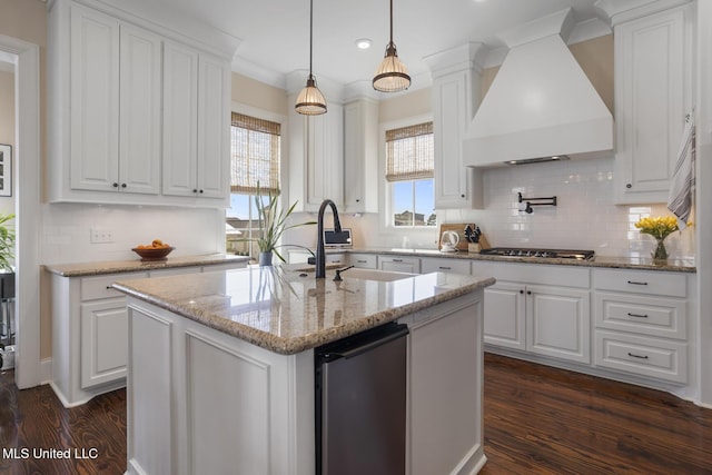 kitchen featuring dark wood-style floors, custom range hood, an island with sink, and white cabinetry