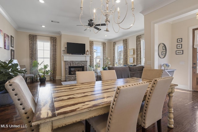 dining room featuring dark wood-style floors, ornamental molding, a fireplace, and visible vents