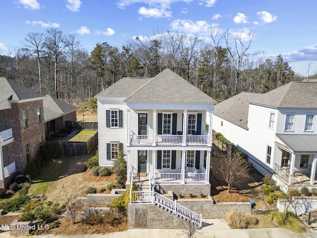 greek revival house with a balcony, covered porch, fence, stairs, and roof with shingles