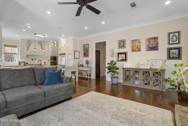 living area with recessed lighting, visible vents, crown molding, and wood finished floors