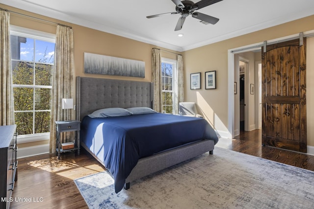 bedroom with a barn door, multiple windows, and wood finished floors