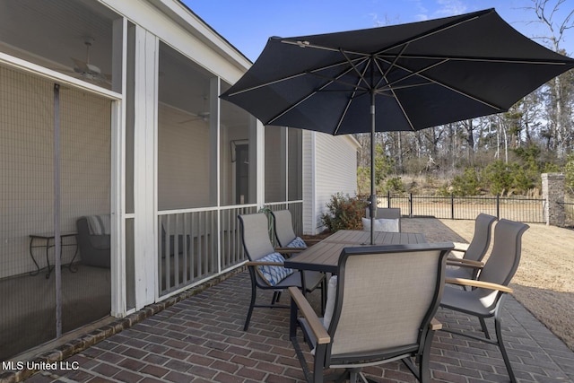 view of patio with outdoor dining space, fence, and a sunroom