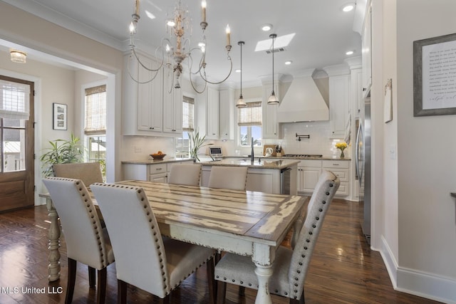 dining room with dark wood finished floors, crown molding, a notable chandelier, visible vents, and baseboards