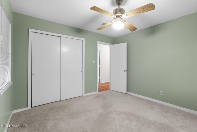 unfurnished bedroom featuring ceiling fan, a closet, and light carpet