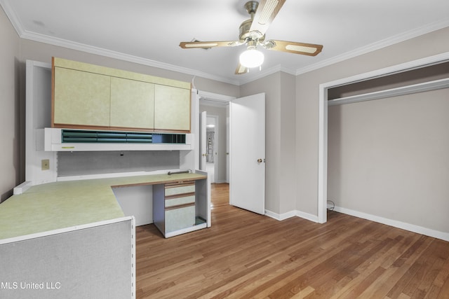 kitchen featuring crown molding, built in desk, and light hardwood / wood-style flooring