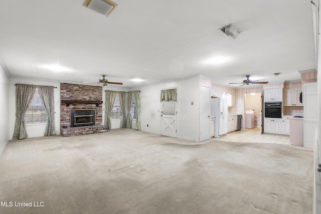 unfurnished living room featuring ceiling fan, crown molding, light colored carpet, and a fireplace