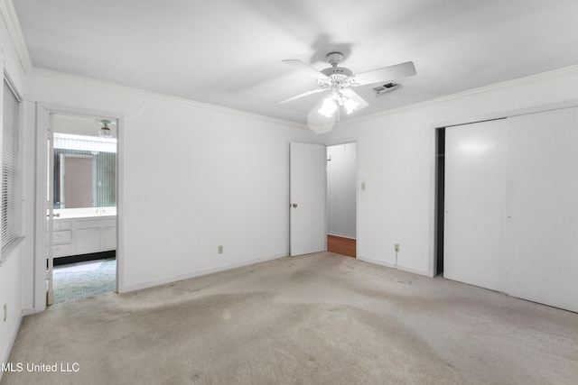 unfurnished bedroom with crown molding, light carpet, ensuite bath, and a closet