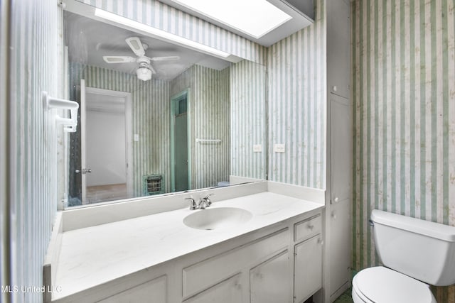 bathroom with vanity, ceiling fan, a skylight, and toilet