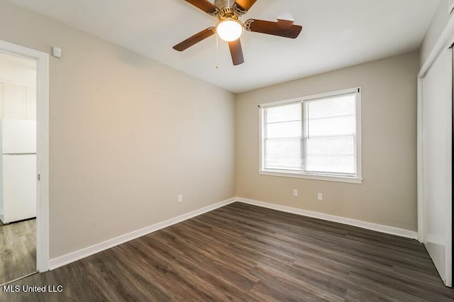 interior space with dark wood finished floors, a closet, freestanding refrigerator, and baseboards